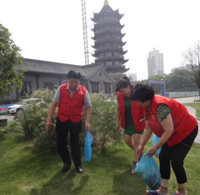 淮安市爱心志愿者服务社社长杨玉琴（中）和志愿在河边捡拾垃圾